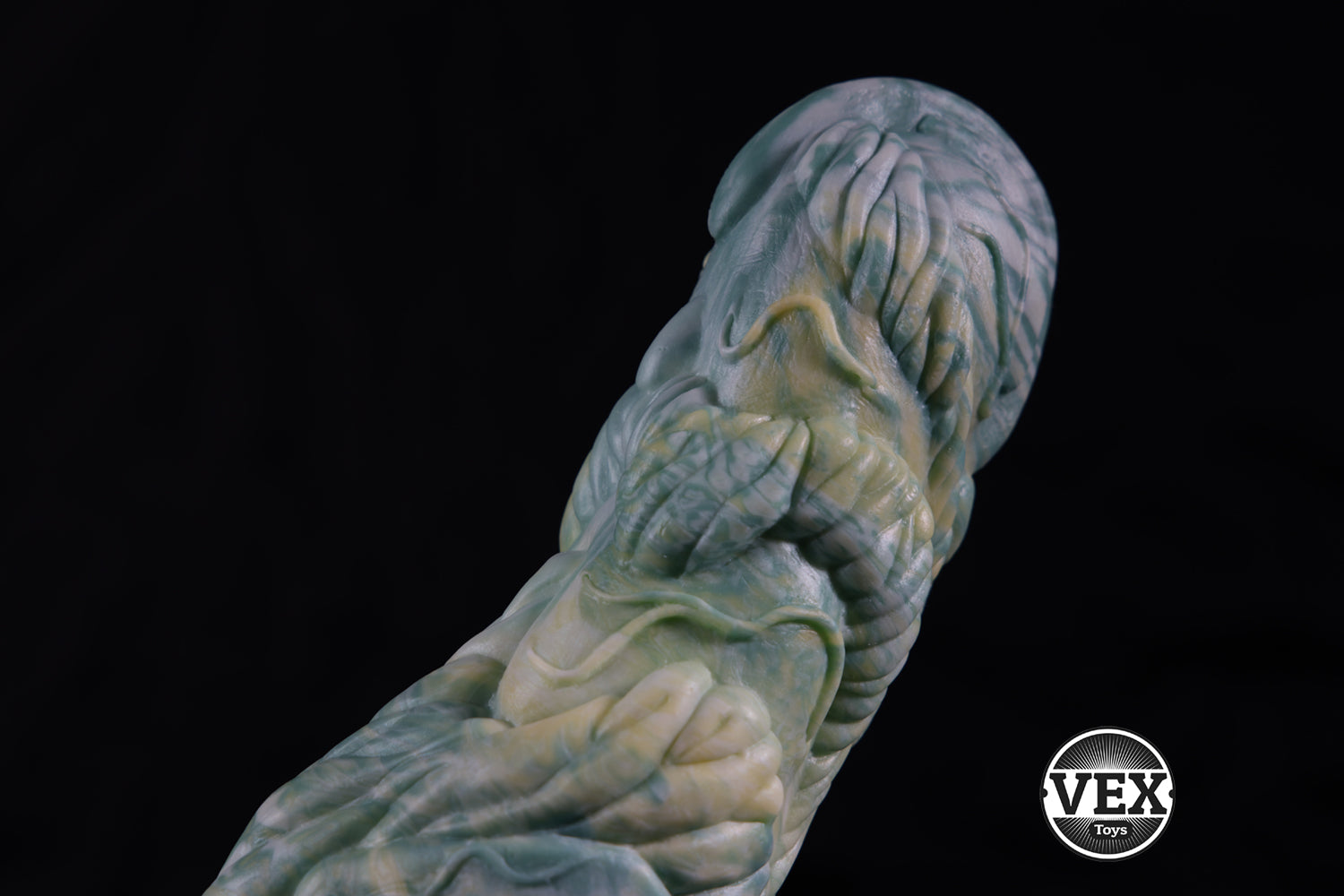 Textured green object with a black background, featuring the VEX logo.